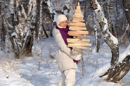 A woman holds a decorative fir tree in her hands and looks into the distanceの写真素材