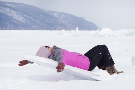 A woman lies on an ice floe frozen in the ice of Lake Baikalの写真素材