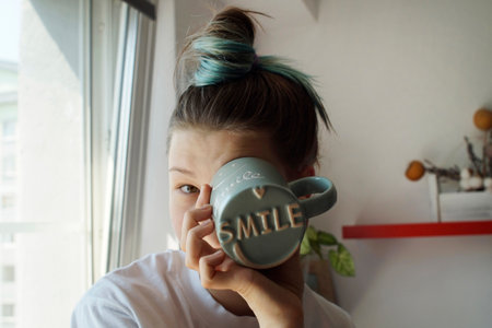 A teenage girl looks into a mug with the inscription smileの写真素材