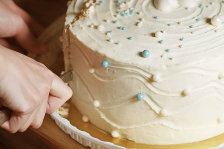 Hands close-up cuts a snow-white cake