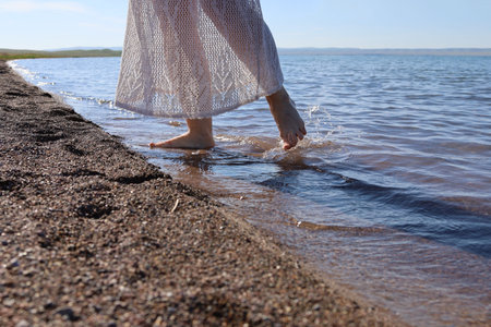 Legs of a woman in a romantic dress on the lake