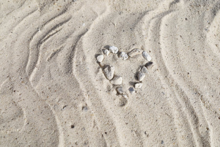 A heart of stones on white wavy sandの写真素材