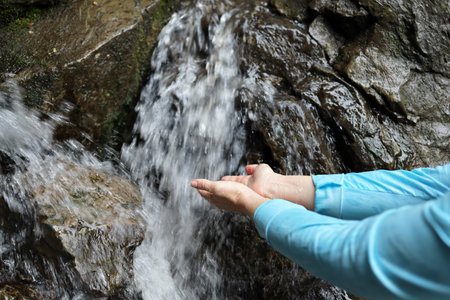 The water of the waterfall flows into the hands of a womanの写真素材