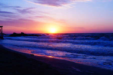 Sunrise on the seashore with waves on a warm summer morning