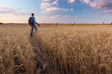 photographer while working search for a story / evening landscape man on the fieldの写真素材