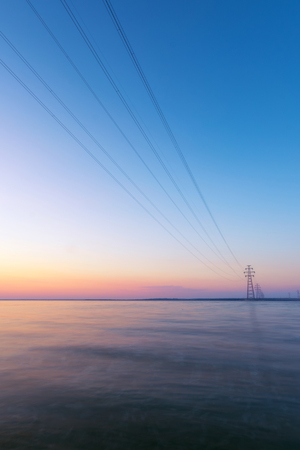 power line standing on the water / technological progress scale is strikingの写真素材
