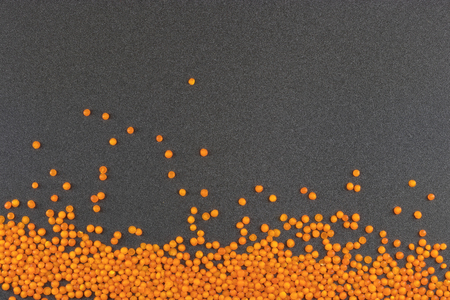 orange lentils on grey background / lentil grains scattered on textured backgroundの写真素材