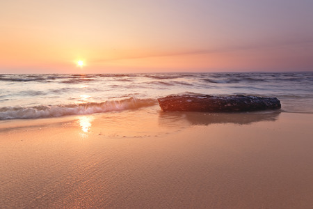 log lying on the shore of an abandoned beach / troubled water dawn morningの写真素材