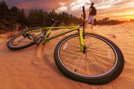 cyclist resting while Hiking / colorful sunset bright cloudsの写真素材
