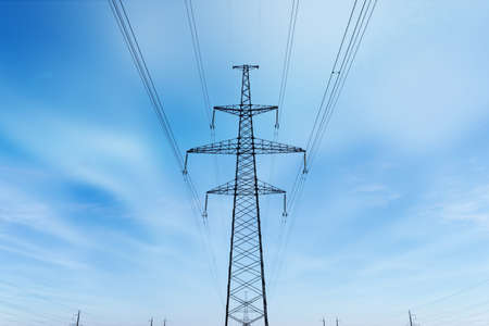 power line summer landscape. passing overhead electricity wire of the support carrying the light and the heat in the houseの写真素材