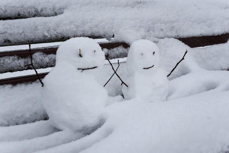 Snowmen sitting on a park benchの写真素材
