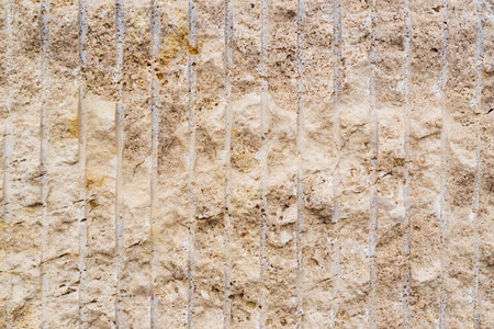 Wall from light yellow stone with vertical lines