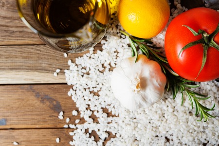 Fresh vegetables and raw rice on wooden table. Shallow field of depth, focus on top of garlicの写真素材