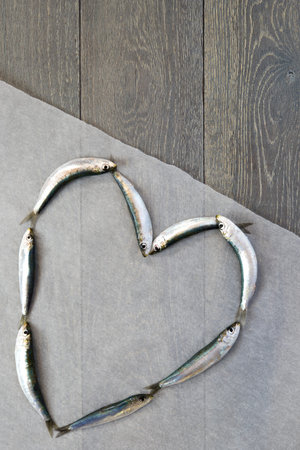Fresh sardine laying in heart form on wooden tableの写真素材