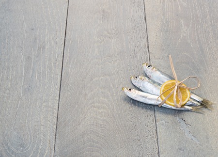 Three sardines wrapped with slice of lemon on wooden tableの写真素材