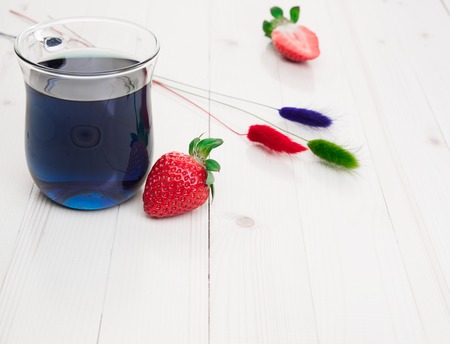 Blue Thai tea with strawberries and dry painted flowers, light wooden table, bright daylight.の写真素材