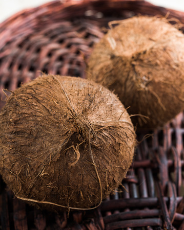 Two coconuts on wicker background, one in focus on foreground and other behind out of focusの写真素材