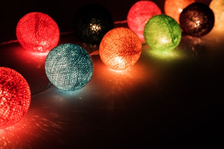 Christmas lights with fiber covers on table, reflections, low keyの写真素材