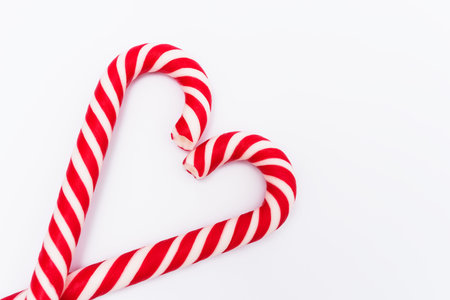 Red-white candy canes in shape of heart on white background