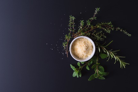 Parmesan and aroma herbs on black background with dramatic side lightの写真素材