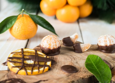 Citruses with chocolate on wooden board, on background whole fruits and fir treeの写真素材