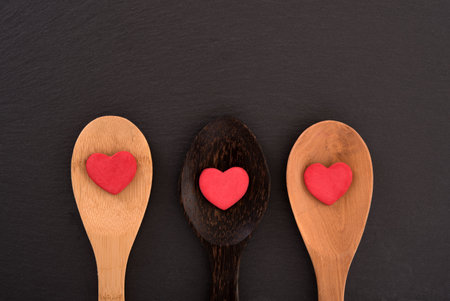 Three spoons with hearts on black board