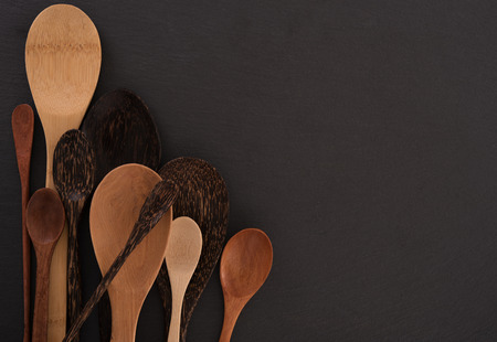 Set of different wooden spoons on black boardの写真素材