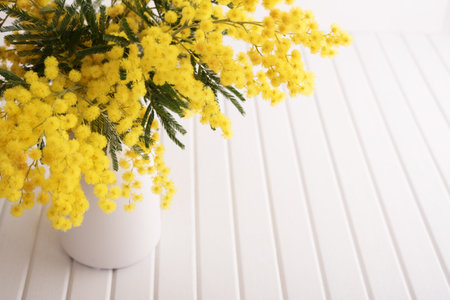 Vase with mimosa flowers on wooden tableの写真素材