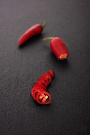 Chili pepper on black stone board, sliced and wholeの写真素材