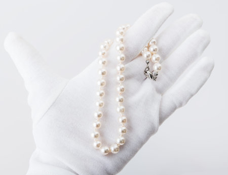 Hand in white glove demonstrates pearl necklaceの写真素材
