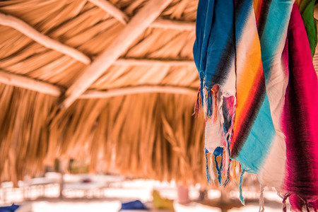 Bright multicolored pareo under sunshade from palm leaves, tonedの写真素材