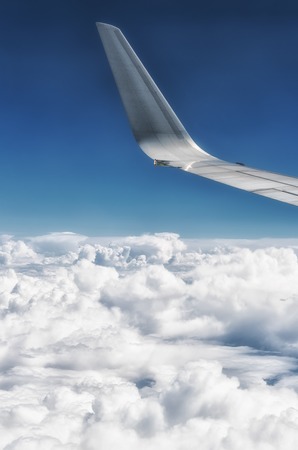 Wing of plane with white clouds belowの写真素材