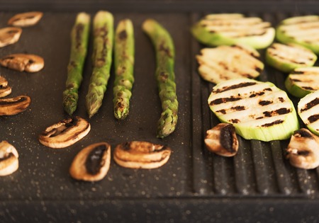 Asparagus, mushrooms and zucchini on electrical grillの写真素材