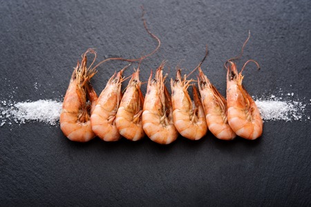 Black stone with cooked shrimps on saltの写真素材