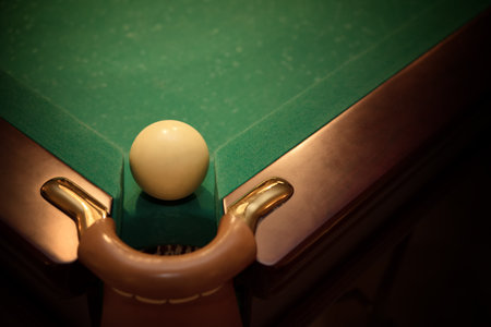 Ball for russian billiards on green table near with hole, vignette