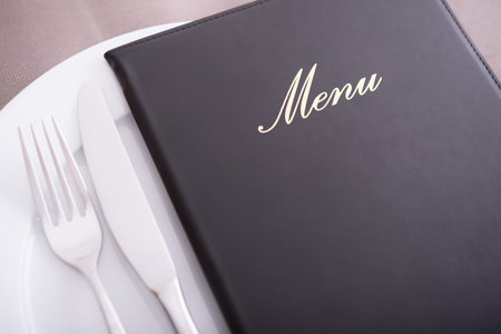 Closeup on menu, arranged table with cutlery and dishes