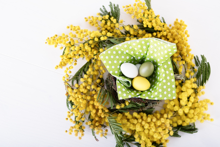 Nest from fresh mimosa and easter eggs inside, top viewの写真素材