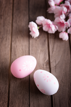 Branches of cherry tree with decorative easter eggs on wooden tableの写真素材