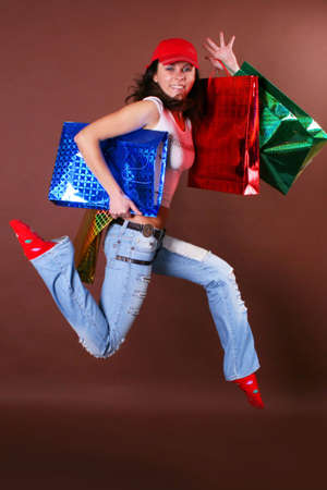 The young beautiful girl with purchases in color packages during shopping on a color backgroundの写真素材