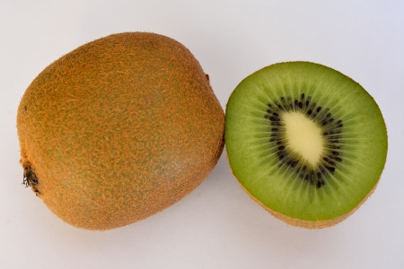 Close up of a kiwi fruit and a piece cut with white backgroundの写真素材