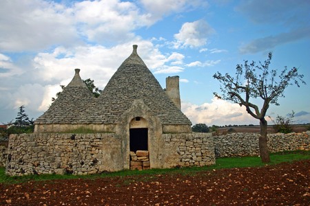 Trulli house assembled of rough stone on a field の写真素材