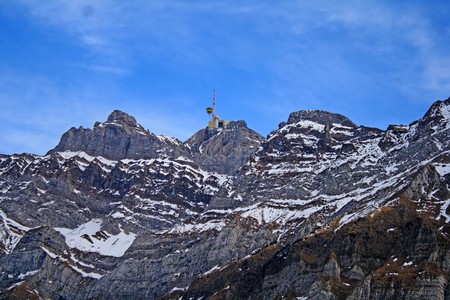 wall and peak of mount Saentis with an hot air balloon passing the peak antenna in evening light の写真素材