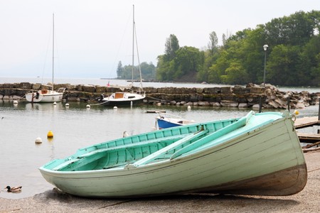 small light green boat onshore in a small harbor on a misty dayの写真素材
