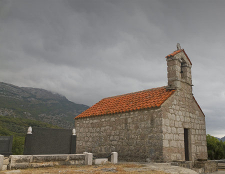 red roofed church stone church in the mountains of Montegro with a stom pulling inの写真素材