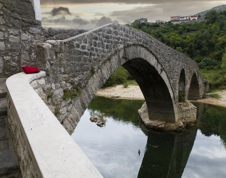 old bridge in the village Rijeka Crnojevica crossing a river with a red pillow to relax in Montenegroの写真素材
