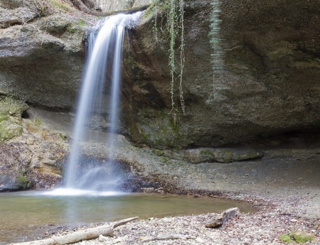 waterfall coming down over hollow cliff in the woods long exposureの写真素材