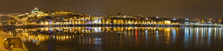 Panorama of Port wine storage village with barrel cellars of Vila Nova de Gaia reflecting in river Duora at night opposite Porto, Portugalの写真素材