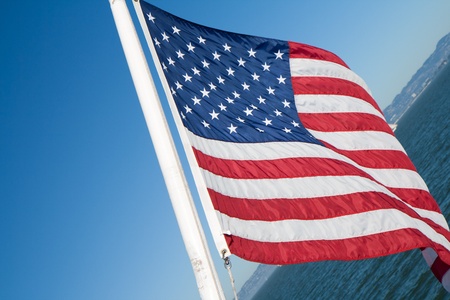 flying Americanflag over water against a blue skyの写真素材