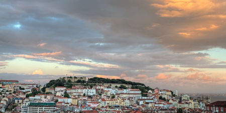historic mediterranean architecture with with castle  Sao Jorge and church at sunset in Lisboa, Portugal, copyspace, concept: dark clouds over Lisbonのeditorial素材