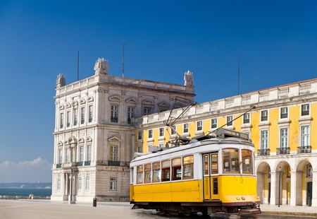 historic classic yellow tram of Lisbon built partially of wood in front of Lisbons central square Praca de Comercio, Portugal のeditorial素材